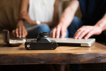 An unrecognizable photographer just closed his laptop after showing a client the photos. The focus is on the vintage camera in the front.