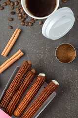 Top view of take away coffee next to chocolate filled and plain churros.