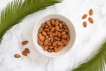 White bowl with toasted natural almonds and palm branches