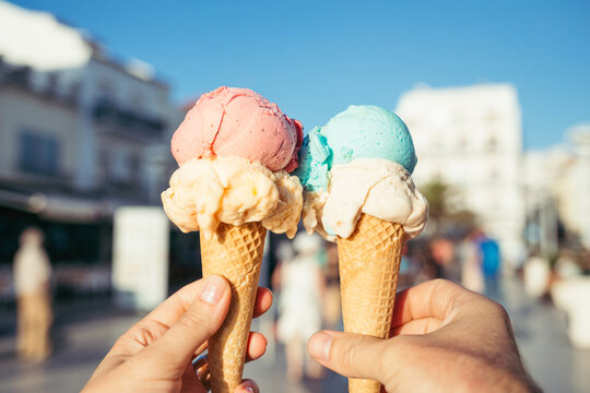 Hands holding ice cream in waffle cones.