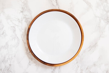 White plate in natural wooden plate on marble table