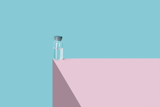 vial with liquid on a pink structure and a blue background. Concept of medicine and coronavirus. copy space