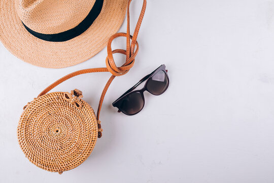 Female summer travel fashion concept. Straw bag, round rattan bag, sunglasses on white background