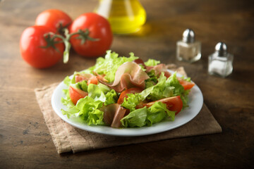Healthy green salad with tomato and prosciutto