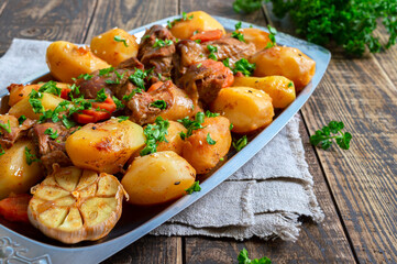 Roast pieces of turkey with vegetables serving on the metal tray on wooden background.