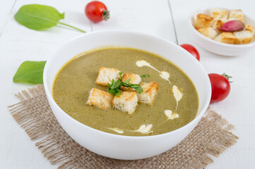 Diet puree soup with spinach and croutons in a white bowl. Proper nutrition.