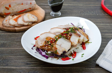 Pork belly with cabbage salad in a white bowl on a wooden background. Chinese cuisine.