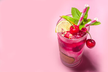 Cold and refreshing summer drink. Cherry cola, limeade, mojito lemonade cocktail with lime and cherries on colorful bright pink background