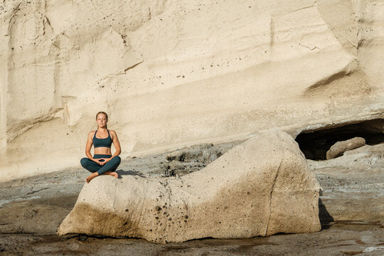 Concentrated woman meditating with mudra gesture outdoors