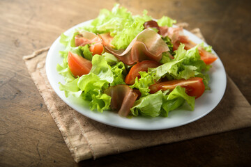 Healthy green salad with tomato and prosciutto