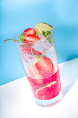 Cold and refreshing summer drink. Strawberry mojito lemonade cocktail with lime and berries on colorful bright pink background