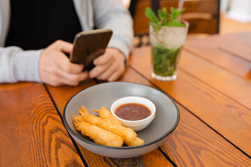 Close-up Photo of man's hands at coffee table with eat using smartphone, mobile device concept