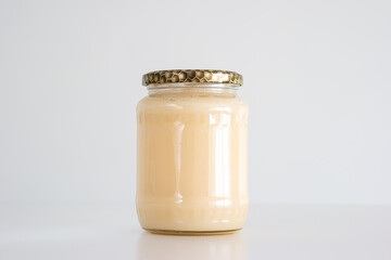 Jar of white crystallized rape flower honey isolated on white close up shot