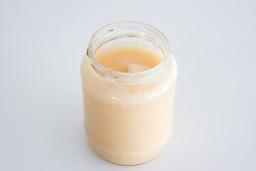 Jar of white crystallized rape flower honey isolated on white close up shot