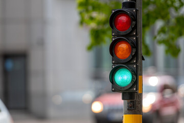 closeup of small traffic semaphore with green light against the backdrop of the city traffic