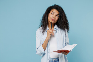Young pensive smart nerd african american girl teen student wear denim clothes write in notebook...