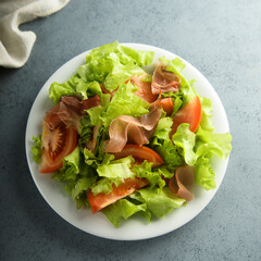 Healthy green salad with tomato and prosciutto