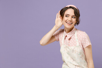 Young curious nosy housewife housekeeper chef cook baker woman wear pink apron t-shirt try to hear you overhear listening intently isolated on pastel violet background studio. Cooking food concept