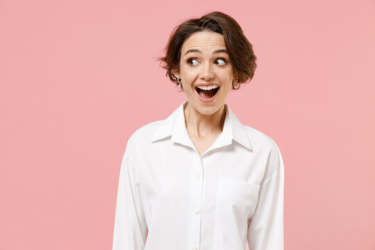 Young fun amazed impressed shocked successful employee business woman corporate lawyer 20s wear classic formal white shirt work in office look aside isolated on pastel pink background studio portrait.