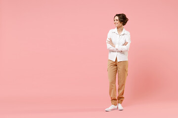 Fototapeta na wymiar Full length young smiling happy successful employee business woman corporate lawyer in classic formal white shirt work in office hold hand crossed look aside isolated on pastel pink background studio