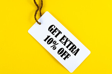 GET EXTRA 10 OFF percent text on a white tag on a yellow paper background