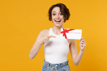 Young surprised woman 20s wear white tank top shirt point index finger on gift certificate coupon...