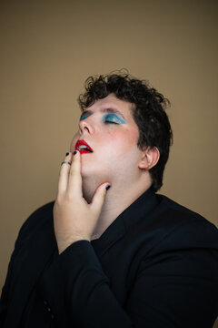 Alluring man with bright makeup touching lips
