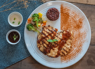 Chicken steak with rice on the white plate.