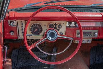 Close up view of a 1960s retro red convertible.  Interior shot of the steering wheel and dashboard,...
