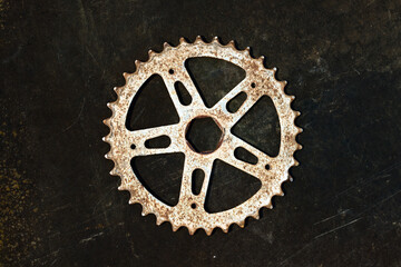 wheel with teeth from a bicycle, spinning gear sprocket on black - obrazy, fototapety, plakaty