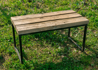 wooden bench with iron legs stands on the grass, outdoor loft furniture