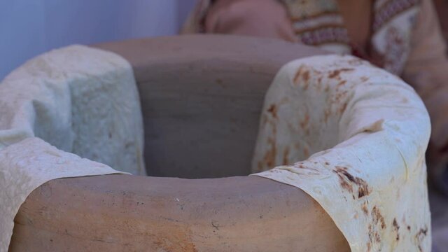 Close view Armenian bread (lavash). The lavash is placed on a clay bowl․ Armenian bread making process,  old traditional way. 