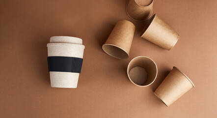 Modern way of Zero waste. One reusable bamboo cup against a lot of disposable paper cups. Coffee and ecology. Beige background