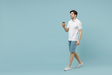Fototapeta na wymiar Full size young happy fun man in white casual basic t-shirt hold takeaway delivery craft paper brown cup coffee to go walk isolated on pastel blue background studio portrait People lifestyle concept