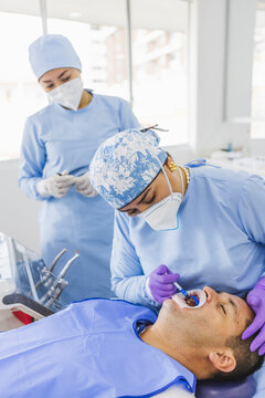 Crop dentist applying fluoride gel on tooth of patient
