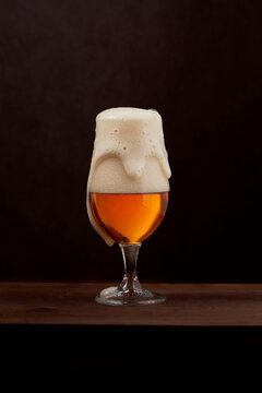 Glass of tasty foamy beer served on wooden table