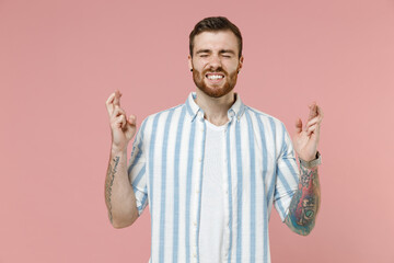Young caucasian unshaven man 20s in blue striped shirt waiting for special moment keep fingers...
