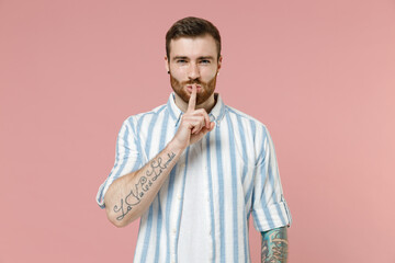 Young secret caucasian unshaven man 20s in blue striped shirt white t-shirt say hush be quiet with...