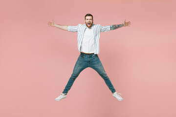 Fototapeta na wymiar Full length young overjoyed excited unshaven man 20s wear blue striped shirt white t-shirt jump high with outstretched hands isolated on pastel pink background studio portrait. Tattoo translate fun