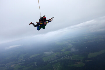 Skydiving. Tandem jump is in the cloudy sky.