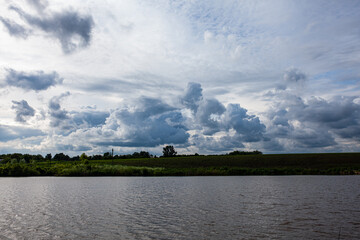 Colorful Spring Landscape On The Lake. Sunny day, many clouds in the sky. View of lake during sunrise