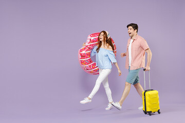 Full length side view two traveler tourist woman man couple in shirt suitcase inflatable donut ring go isolated on purple background Passenger travel abroad weekend getaway Air flight journey concept.