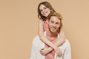 Young happy parent man have fun with cute child teen girl in casual pastel clothes Daddy little kid daughter look camera hug stand behind isolated on beige background Father's Day Love family concept