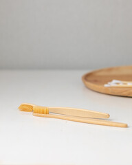 daily human hygiene, cotton swabs and cotton pads, a woman's hand holding bamboo toothbrushes on a light background in a glass or against the background of a wooden tray, eco-friendly personal hygiene