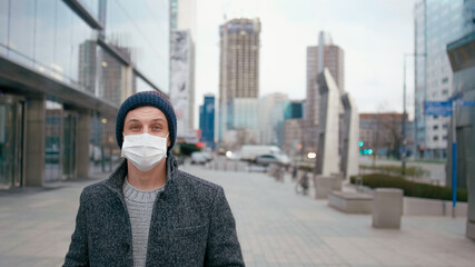 SARS-CoV-2 COVID-19 Coronavirus Pandemic Outbreak: Man Standing in Surgical Face Mask in City Downtown Street and Looks to Camera. Picture with Copy Space