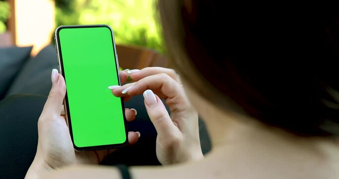Woman using smartphone with green screen outdoors &ndash; mockup template for mobile app or website