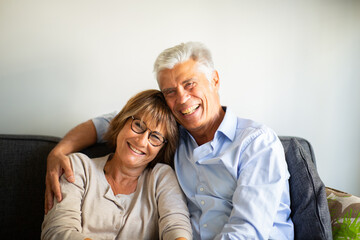 Obraz na płótnie Canvas Close up smiling happy older couple sitting on sofa together