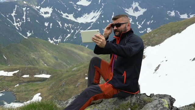 Young man taking selfie photo with tablet computer in the mountains