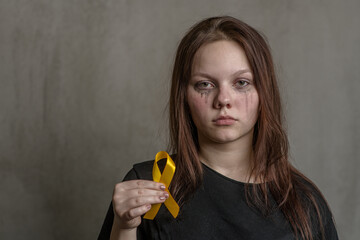 Tear-stained teen girl holds yellow ribbon. Concept of suicide problems and their prevention. Empty...