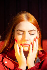 Close up portrait of a young red haired woman with red manicure, minimalism concept, monochrome,...